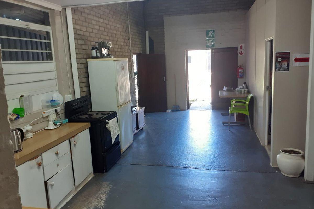 A functional commercial kitchen area featuring exposed brick walls, built-in cabinetry, and a freestanding stove, leading to an exterior exit.
