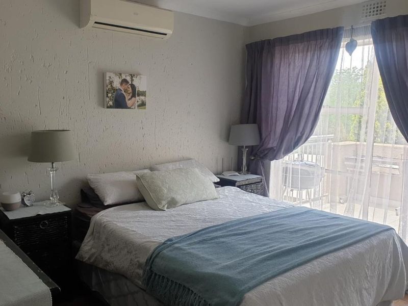 A bedroom featuring a split-system air conditioner, textured walls, and a sliding glass door providing access to an outdoor balcony area.