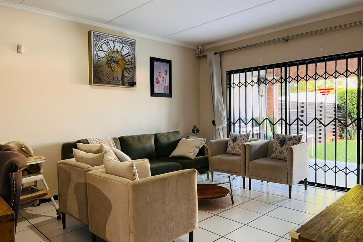 A comfortable living room featuring tiled flooring and a sliding glass door with a security gate, providing direct access to the outdoor area.