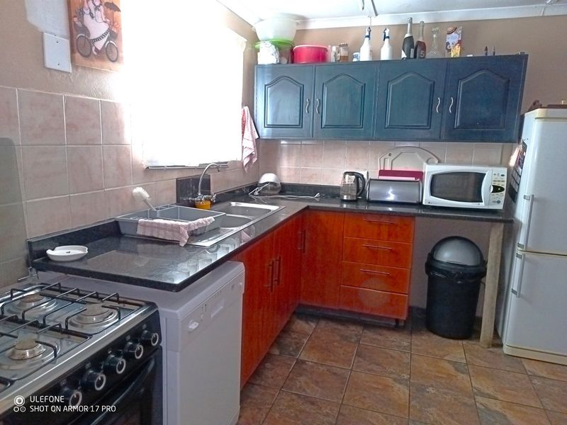 Functional kitchen featuring granite countertops, dual-tone cabinetry, tiled backsplash, and a gas stove, offering a practical layout for daily meal preparation.