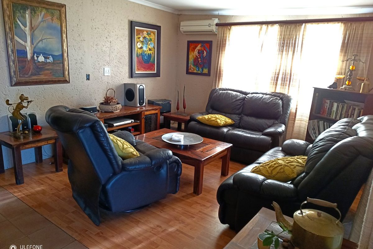 A comfortable living room featuring textured walls, laminate flooring, and a wall-mounted air conditioning unit.