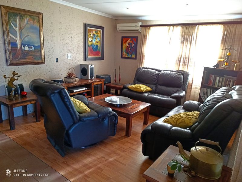 A comfortable living room featuring textured walls, laminate flooring, and a wall-mounted air conditioning unit.
