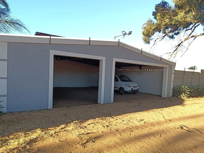 A functional double carport structure with a concrete finish, providing sheltered parking space on the farm property.