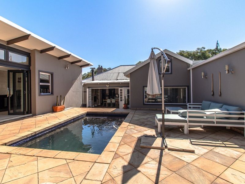 A well-maintained outdoor pool area featuring stone paving, integrated swimming pool, and direct access to the home through large bi-fold doors.
