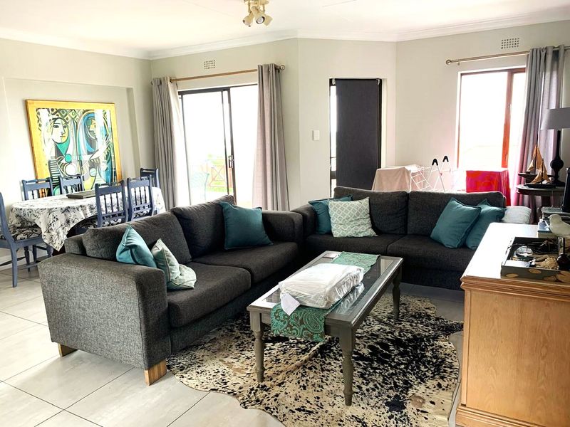 Spacious open-plan living and dining area featuring tiled flooring, neutral walls, and large sliding glass doors providing access to the outdoor space.