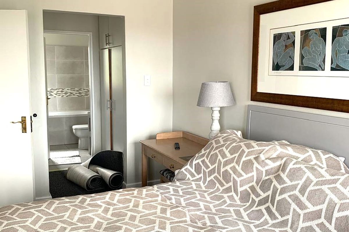 A well-maintained bedroom featuring neutral walls, coving, and direct access to an en-suite bathroom with built-in storage.