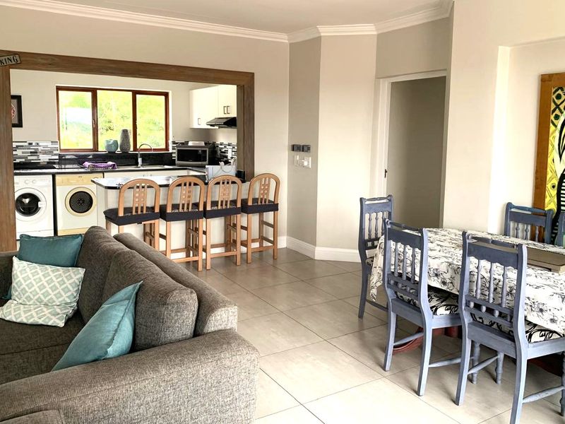 Open-plan living and dining area featuring tiled floors, coving, and a functional kitchen with granite countertops and integrated cabinetry.