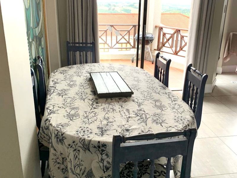 A bright dining area featuring tiled flooring and a sliding glass door that opens onto a balcony with scenic views.