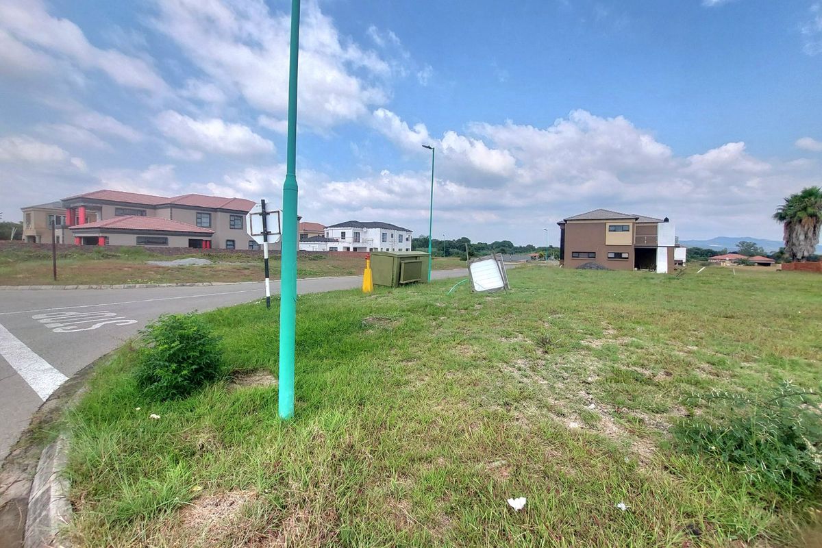 A street view of a residential vacant land plot in a developed estate with paved roads and surrounding residential properties.
