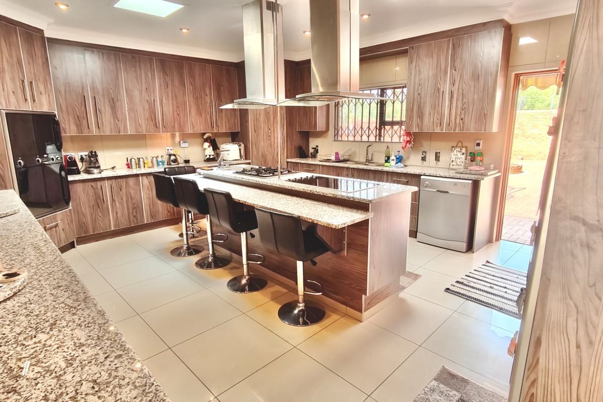 Spacious kitchen featuring wood-finish cabinetry, granite countertops, a central island with a breakfast bar, and integrated stainless steel appliances.
