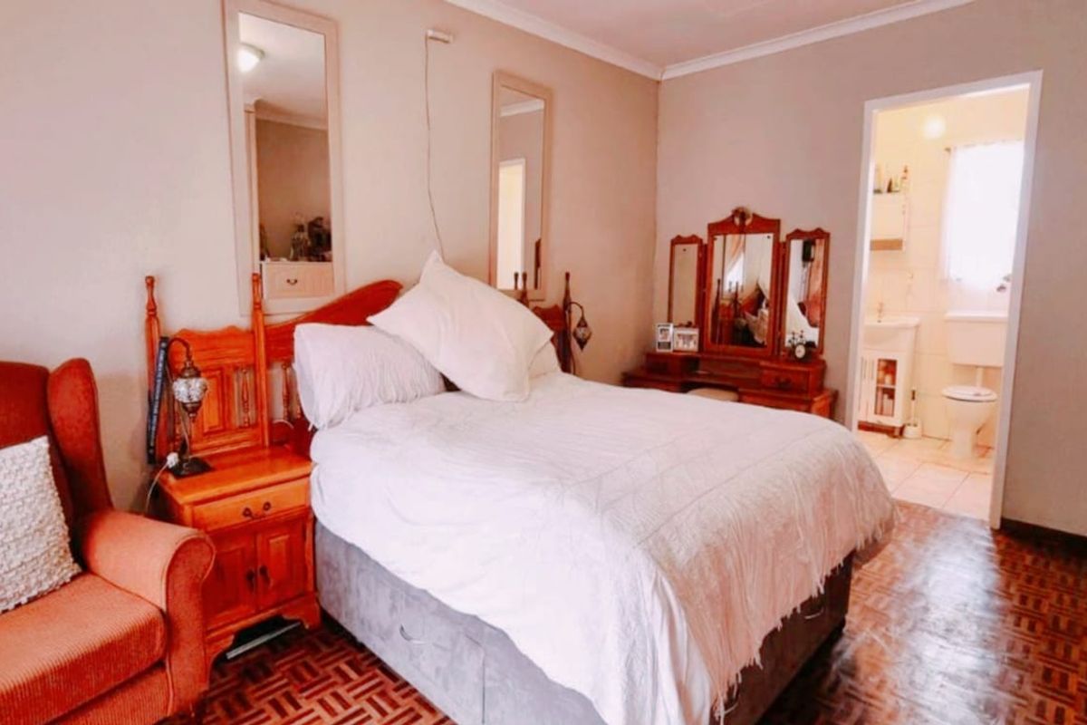 A bedroom featuring parquet flooring and coving, with an adjoining en-suite bathroom visible through the doorway.
