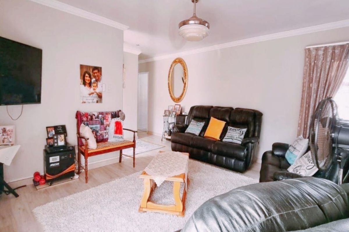 A comfortable living room featuring laminate flooring, decorative coving, and a ceiling fan, providing a functional and inviting space for relaxation.