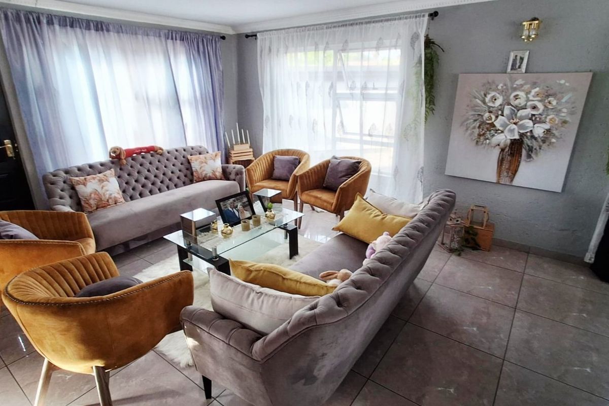 A well-lit living room featuring large windows, tiled flooring, and decorative crown molding, creating a comfortable and inviting space.
