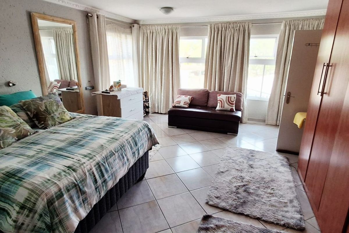 Spacious bedroom featuring tiled flooring, built-in wardrobe storage, and decorative ceiling cornicing, offering a functional layout with ample natural light.