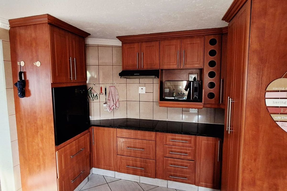 A functional kitchen featuring warm-toned wooden cabinetry, granite countertops, a built-in oven, and a tiled backsplash.