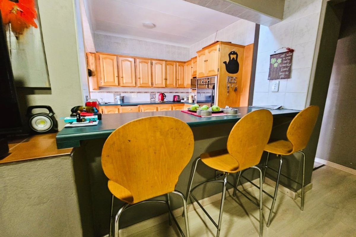 A functional kitchen featuring timber cabinetry, a tiled splashback, and a breakfast bar counter with integrated oven.