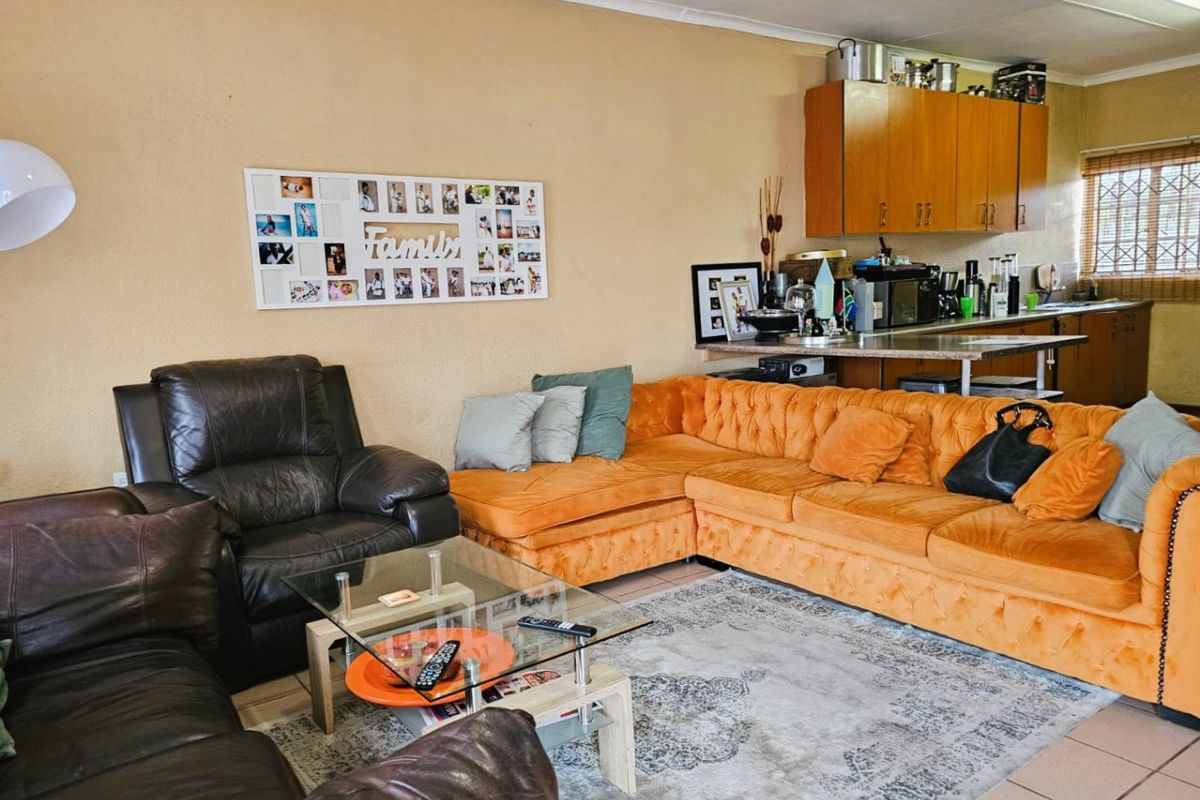 Open plan living area featuring a kitchen with wooden cabinetry and a breakfast counter, seamlessly connected to the lounge space.