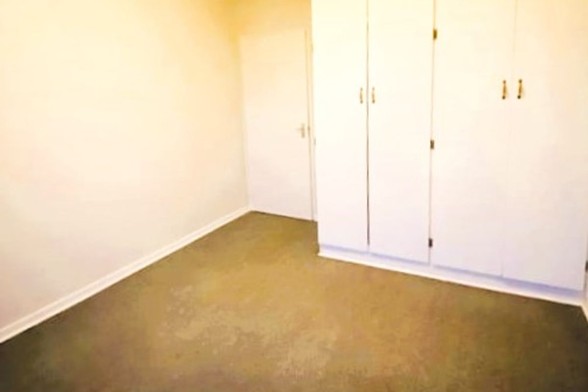 An empty bedroom featuring neutral walls, carpeted flooring, and ample built-in cupboard storage space.