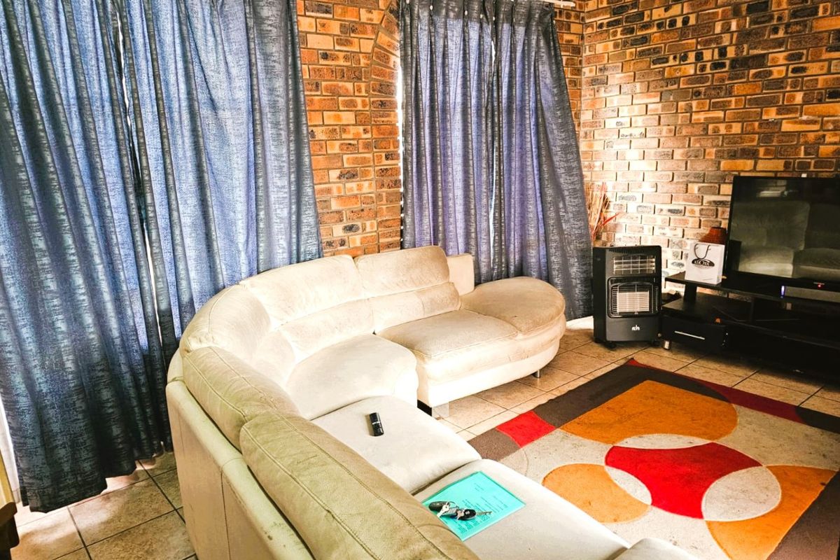 A living room featuring exposed brick walls and tiled flooring, providing a rustic aesthetic base for potential interior updates.