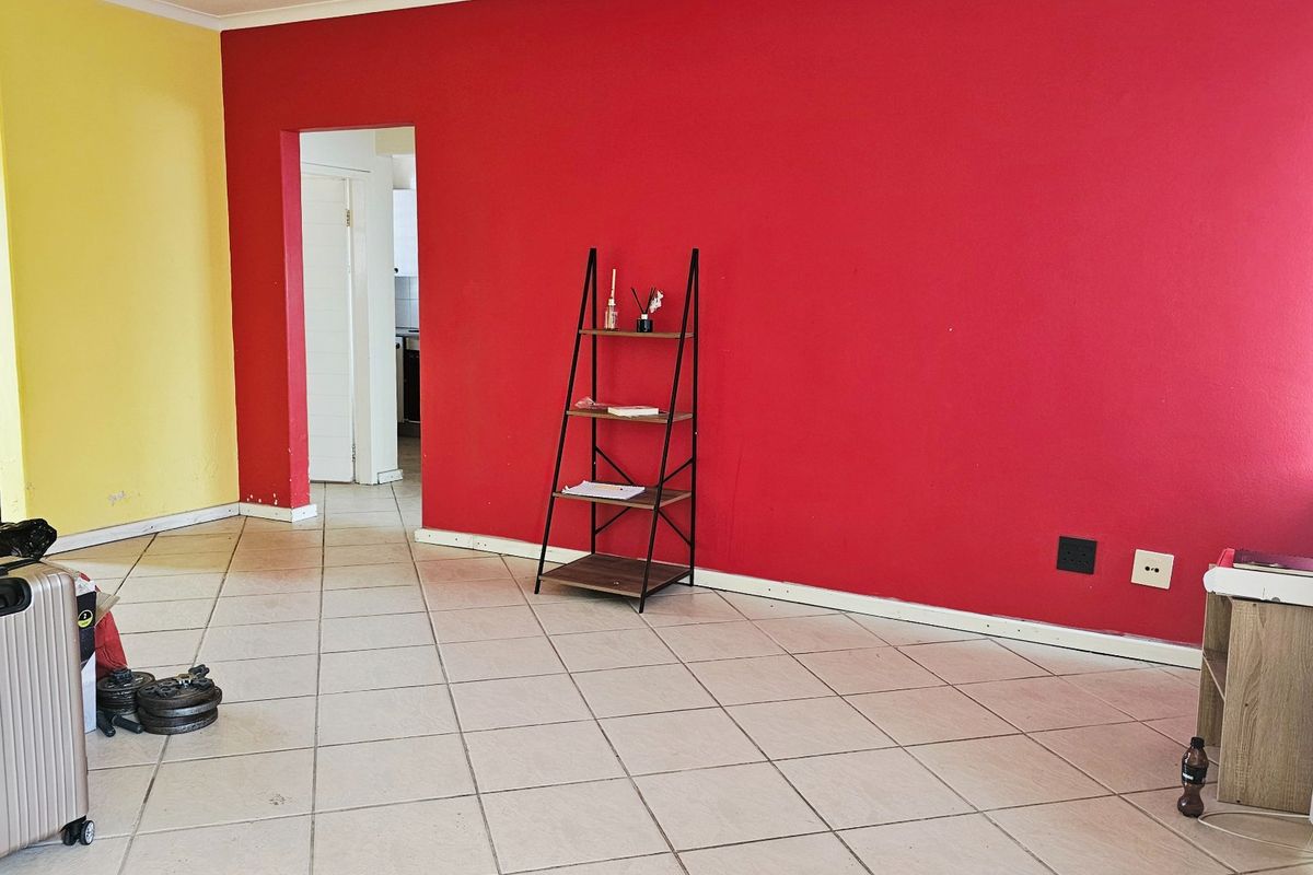 A spacious living area featuring tiled flooring and bold accent walls, offering a blank canvas for personalization and interior design updates.