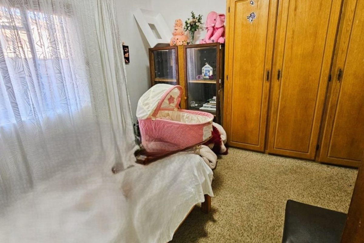 A bedroom featuring built-in wooden cupboards and carpeted flooring, offering a functional space with potential for modernization.