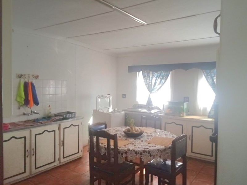 A functional kitchen area featuring built-in cabinetry, tiled flooring, and a tiled splashback, offering a practical layout for daily use.