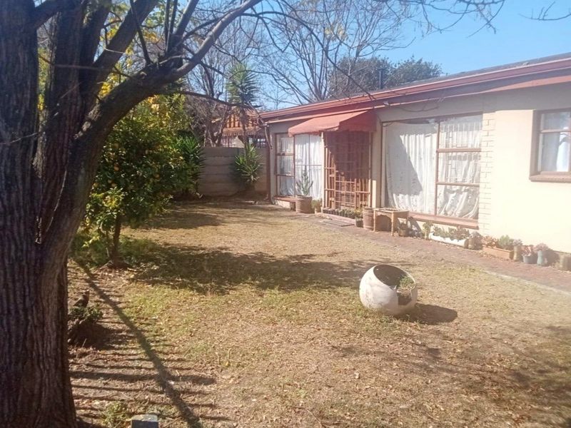 Rear view of the property featuring a brick facade, large windows, and a private garden area with a paved walkway.