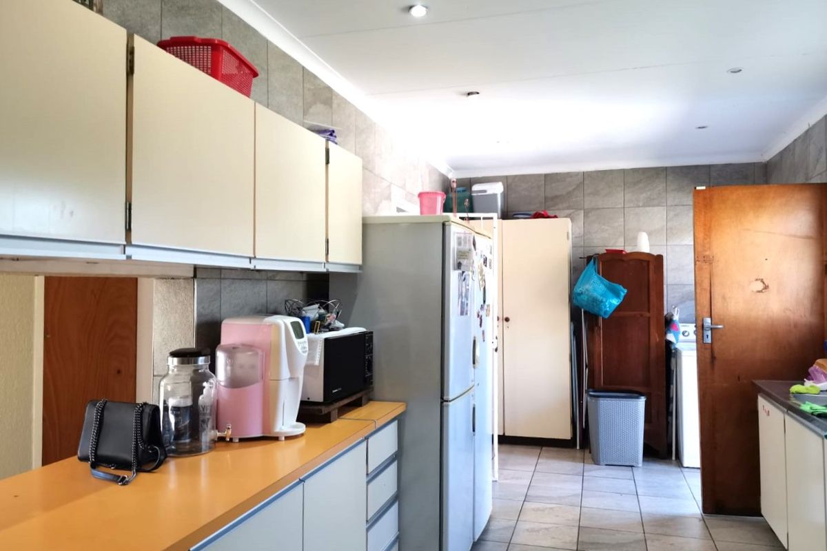 A functional kitchen space featuring tiled flooring, wall-mounted cabinetry, and laminate countertops, offering potential for modernization and aesthetic updates.
