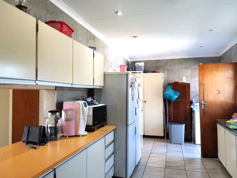 A functional kitchen space featuring tiled flooring, wall-mounted cabinetry, and laminate countertops, offering potential for modernization and aesthetic updates.