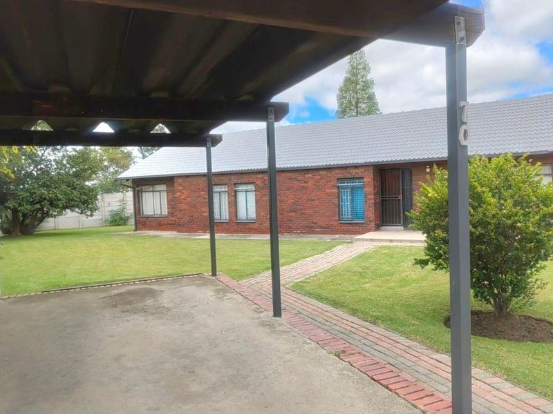 A covered patio area overlooking a well-maintained garden and the brick exterior of the main house.
