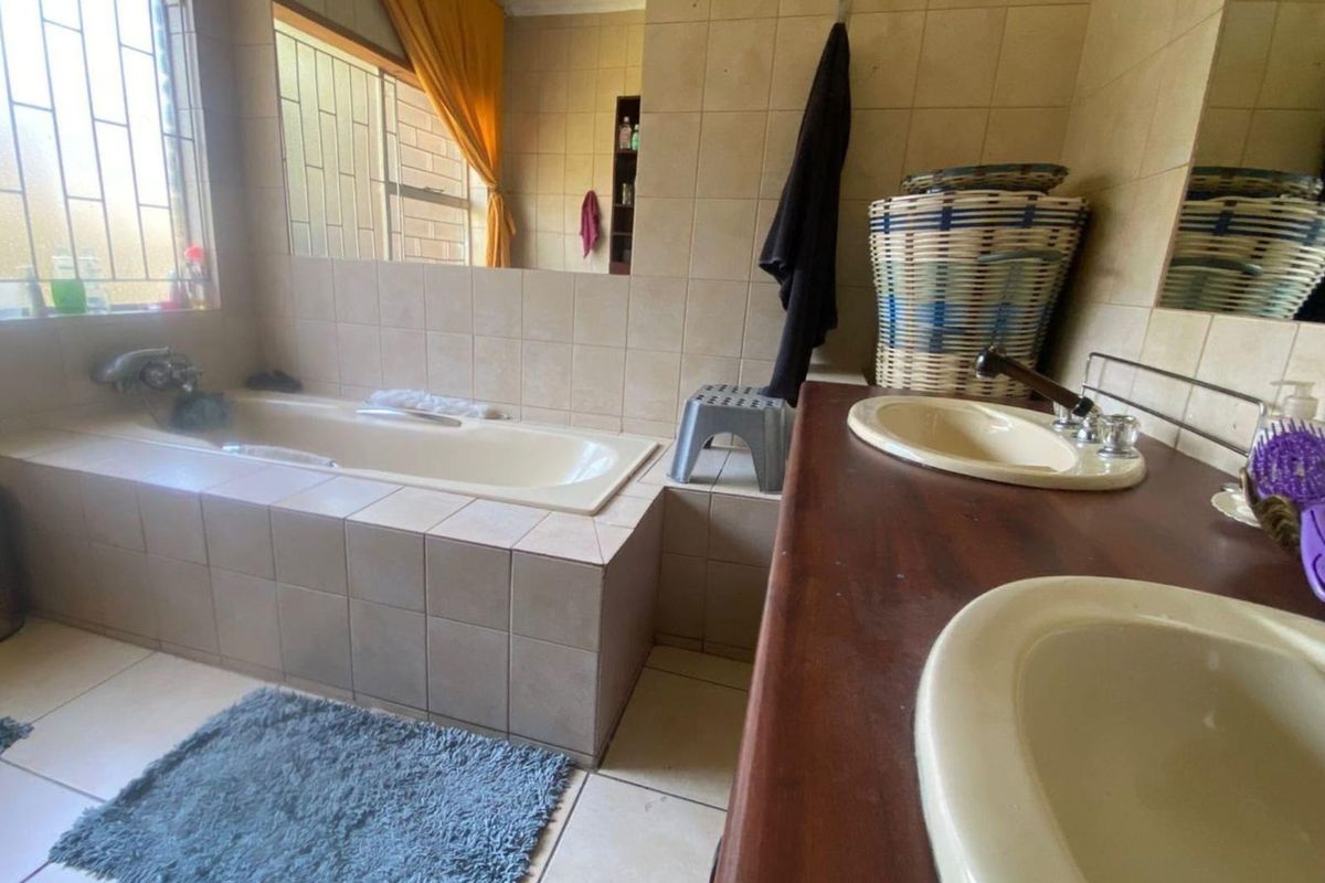 A dated bathroom featuring a built-in bathtub, double vanity with integrated sinks, and tiled finishes throughout.