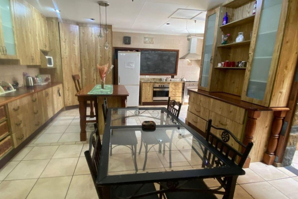 Spacious kitchen featuring extensive built-in wooden cabinetry, tiled flooring, and integrated appliances, offering a functional layout with ample storage and preparation space.