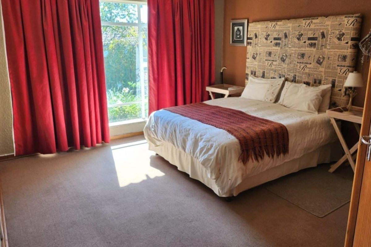 A bedroom featuring carpeted flooring and a large window that allows for natural light.