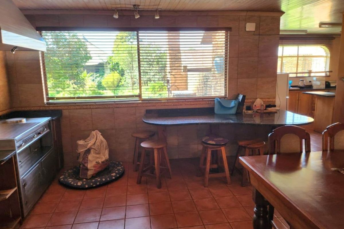 A functional kitchen featuring granite countertops, a built-in stove with extractor fan, and a breakfast nook area with tiled flooring.