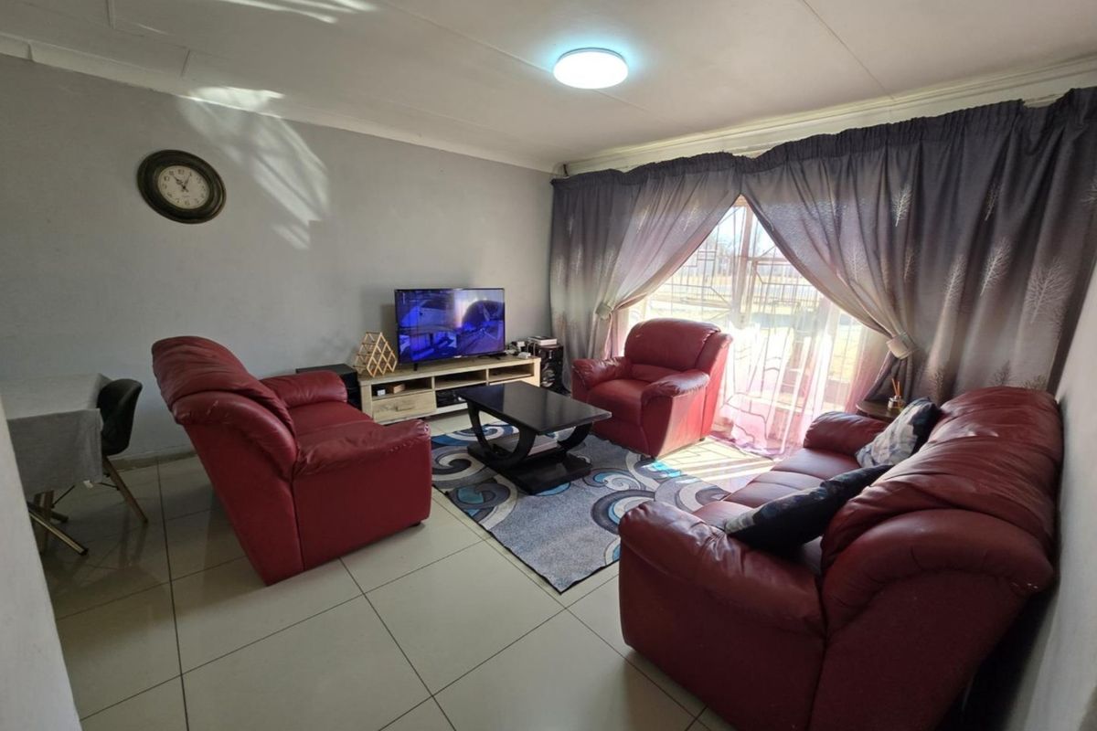 A comfortable living room featuring tiled flooring, a coved ceiling, and a sliding glass door that provides natural light.
