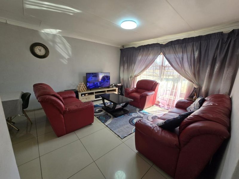 A comfortable living room featuring tiled flooring, a coved ceiling, and a sliding glass door that provides natural light.