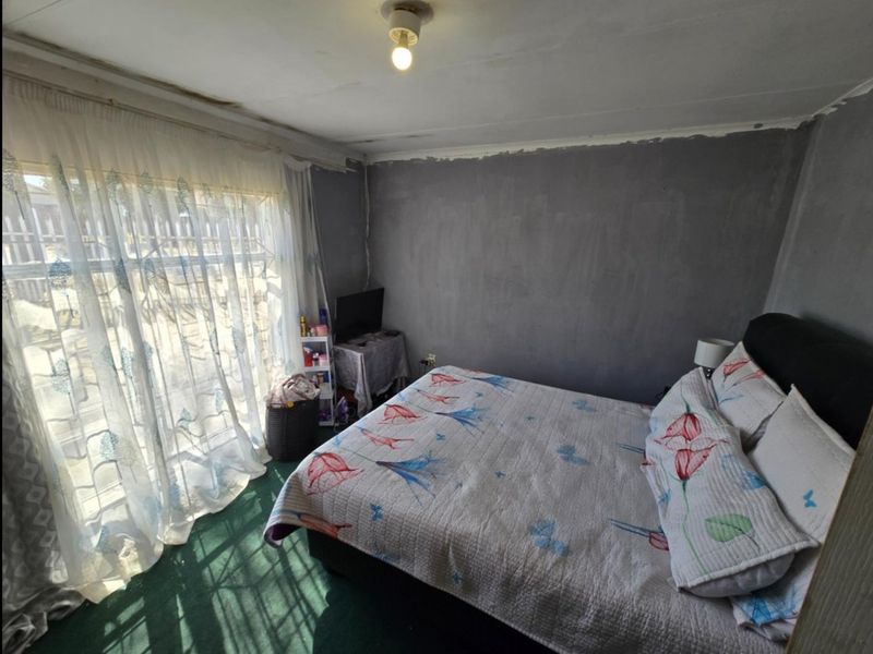 A bedroom featuring a large sliding glass door and carpeted flooring, currently requiring cosmetic updates to the walls and ceiling finishes.