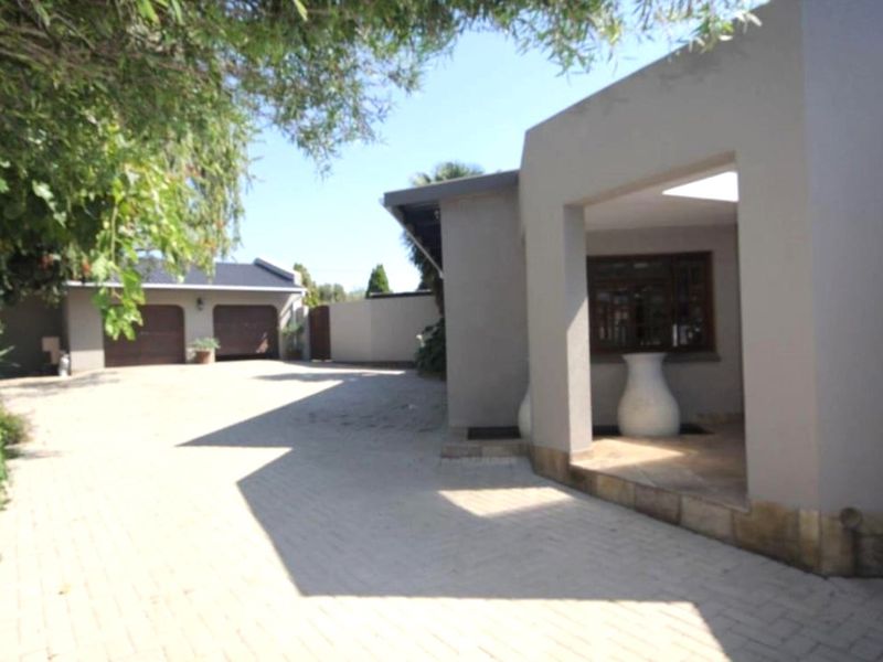 A view of the property exterior featuring a paved driveway, covered entrance area, and a detached garage structure.