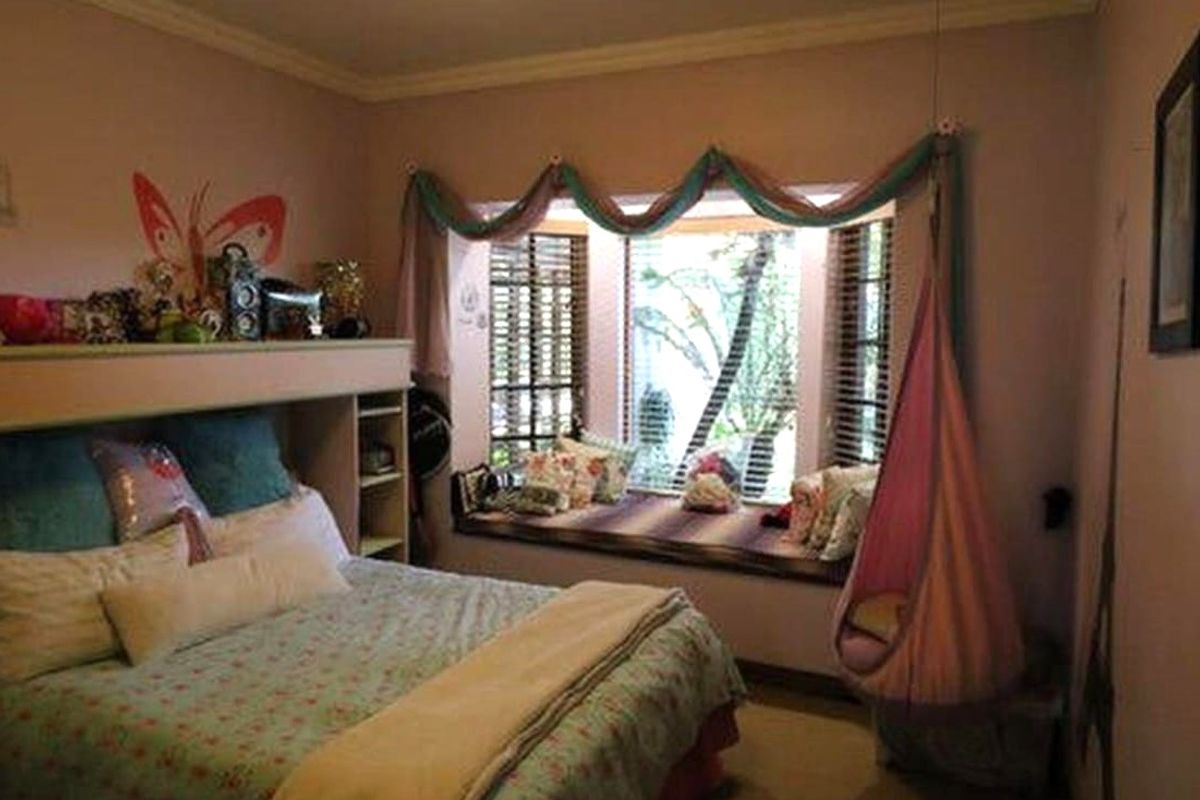 A bedroom featuring a built-in headboard unit with integrated shelving and a window seat with wooden blinds.