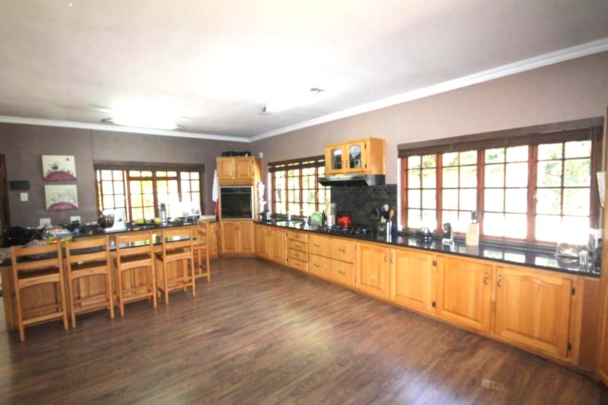 Spacious kitchen featuring extensive wooden cabinetry, dark granite countertops, a built-in oven, and a breakfast bar island with ample natural light from large windows.