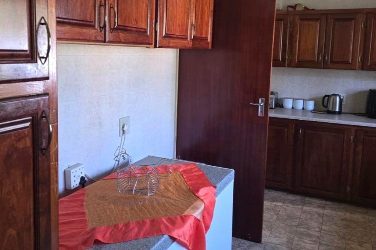 A functional kitchen featuring traditional wooden cabinetry, laminate countertops, and tiled flooring, offering a classic layout with ample storage space.