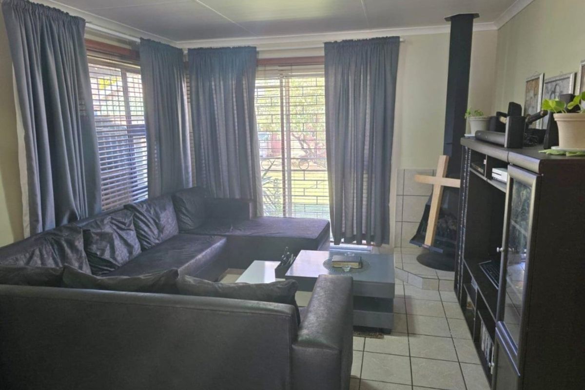 A living room featuring tiled flooring, a freestanding fireplace, and a sliding glass door providing access to the exterior.