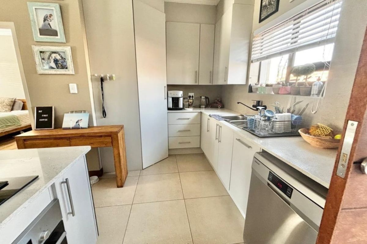 A functional kitchen featuring light-toned cabinetry, stone countertops, tiled flooring, and integrated appliance space, offering a clean and practical layout.