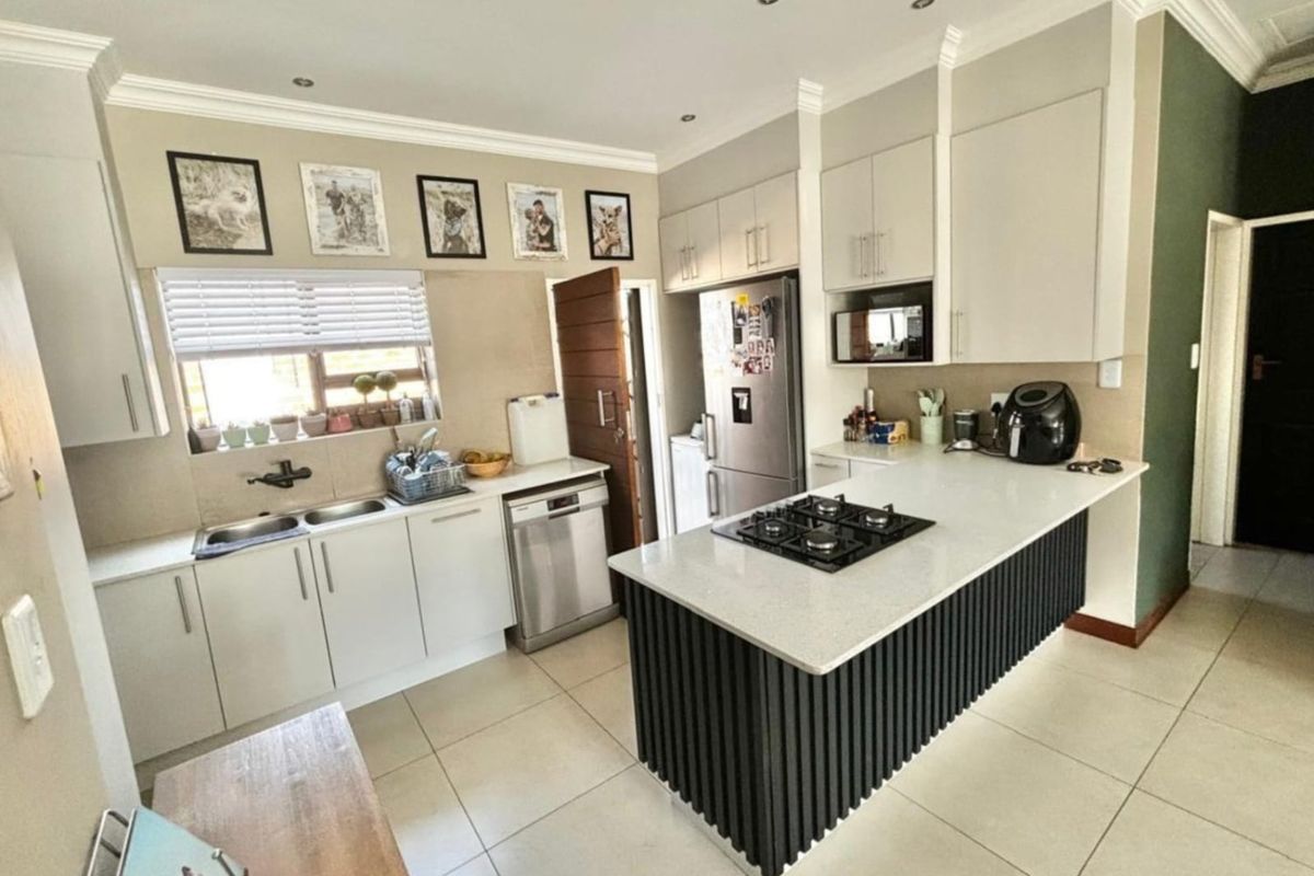 Modern kitchen featuring a central island with a built-in gas hob, stone countertops, ample cabinetry, and tiled flooring.