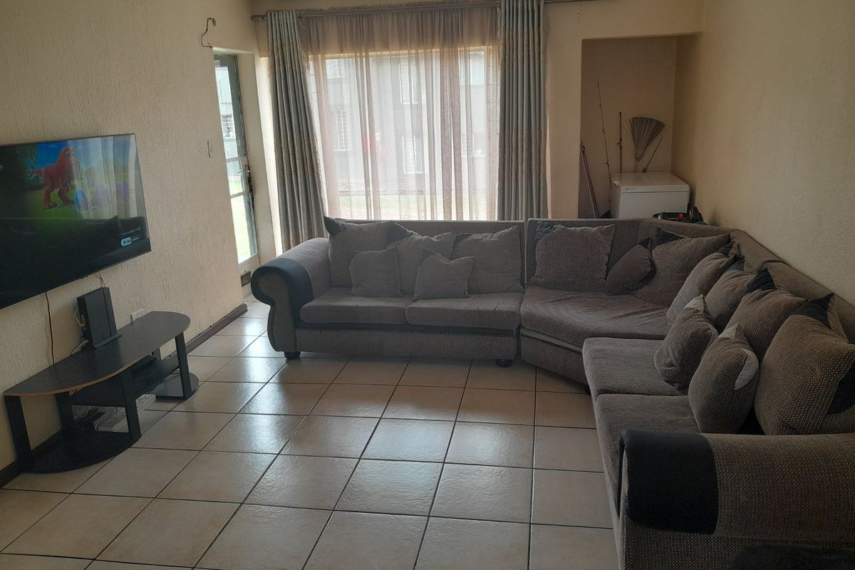 A living room featuring tiled flooring and a sliding glass door providing access to the exterior.