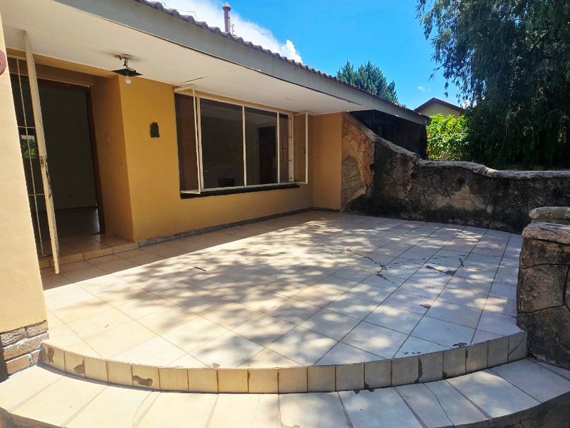 A spacious outdoor patio area featuring tiled flooring, stone retaining walls, and direct access to the interior living space.