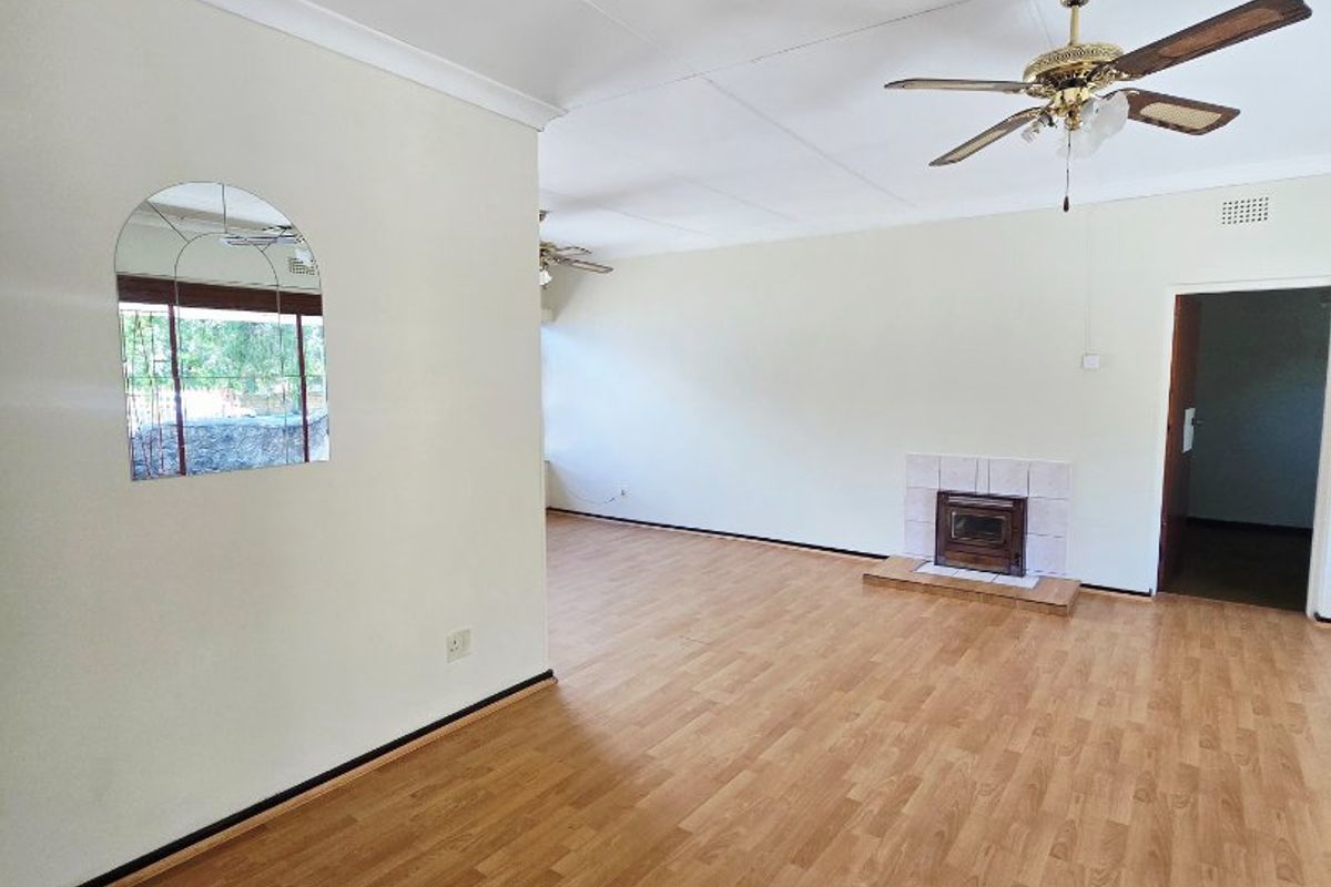 Spacious living area featuring laminate flooring, a built-in fireplace, and a ceiling fan, offering a clean, neutral canvas for interior design.