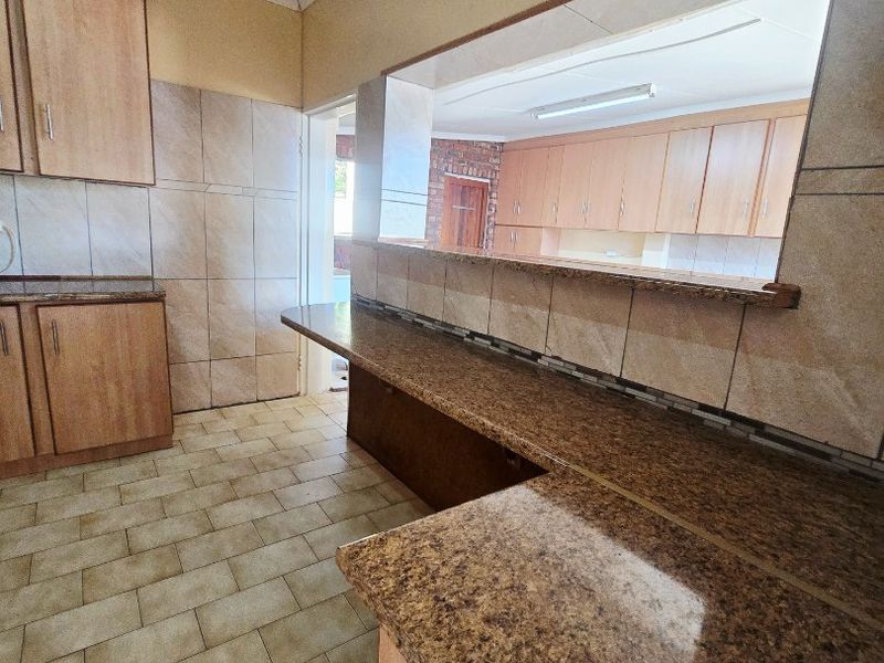A functional kitchen featuring laminate cabinetry, granite countertops, and a convenient pass-through window connecting to the adjacent living space.