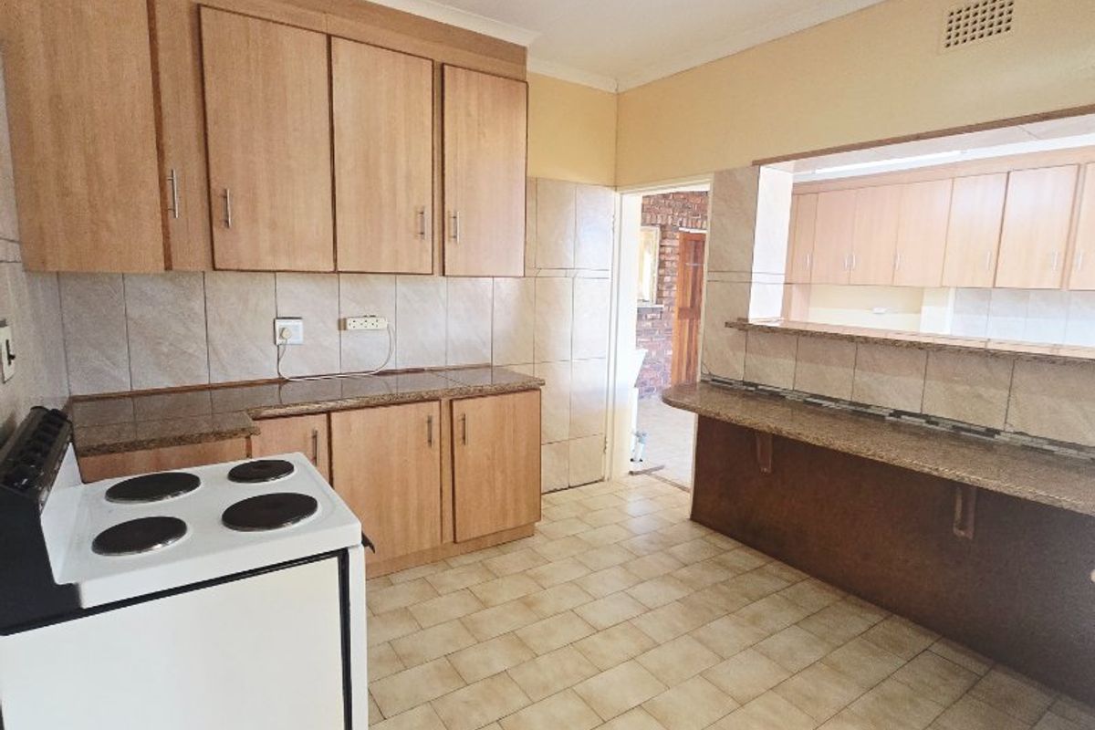 A functional kitchen featuring light wood cabinetry, granite countertops, a breakfast bar, and tiled flooring, offering a clean and practical workspace.