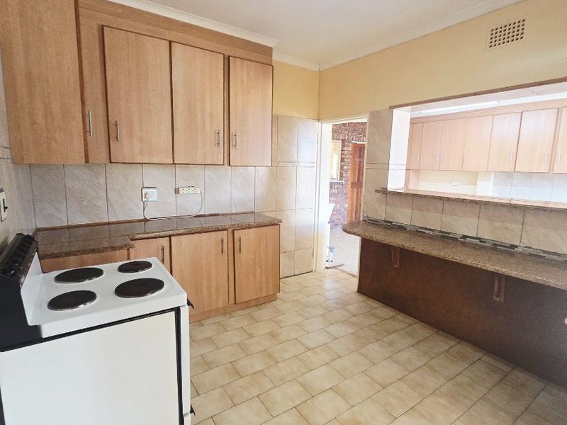 A functional kitchen featuring light wood cabinetry, granite countertops, a breakfast bar, and tiled flooring, offering a clean and practical workspace.